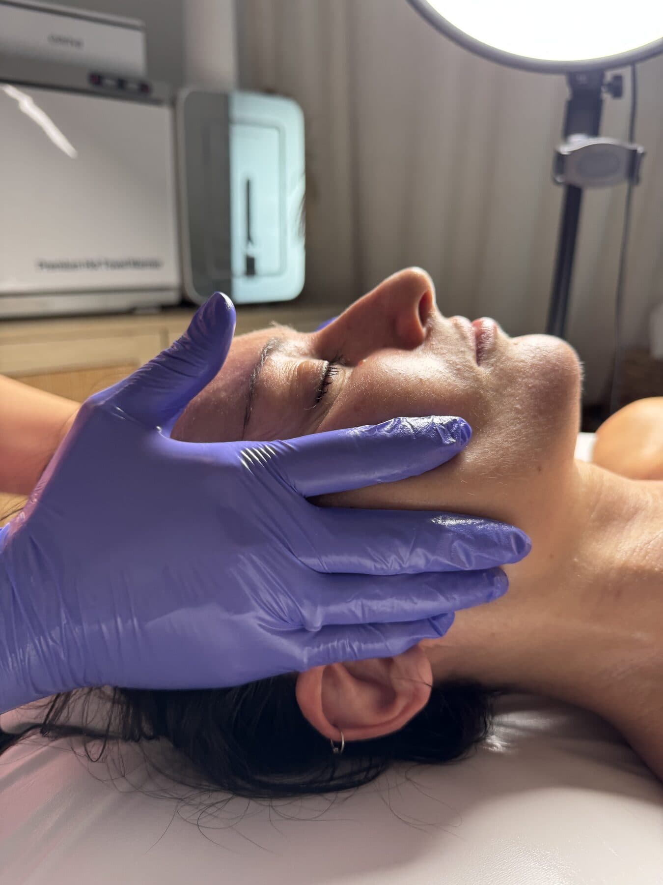 Esthetician cradling a guest's face during a facial